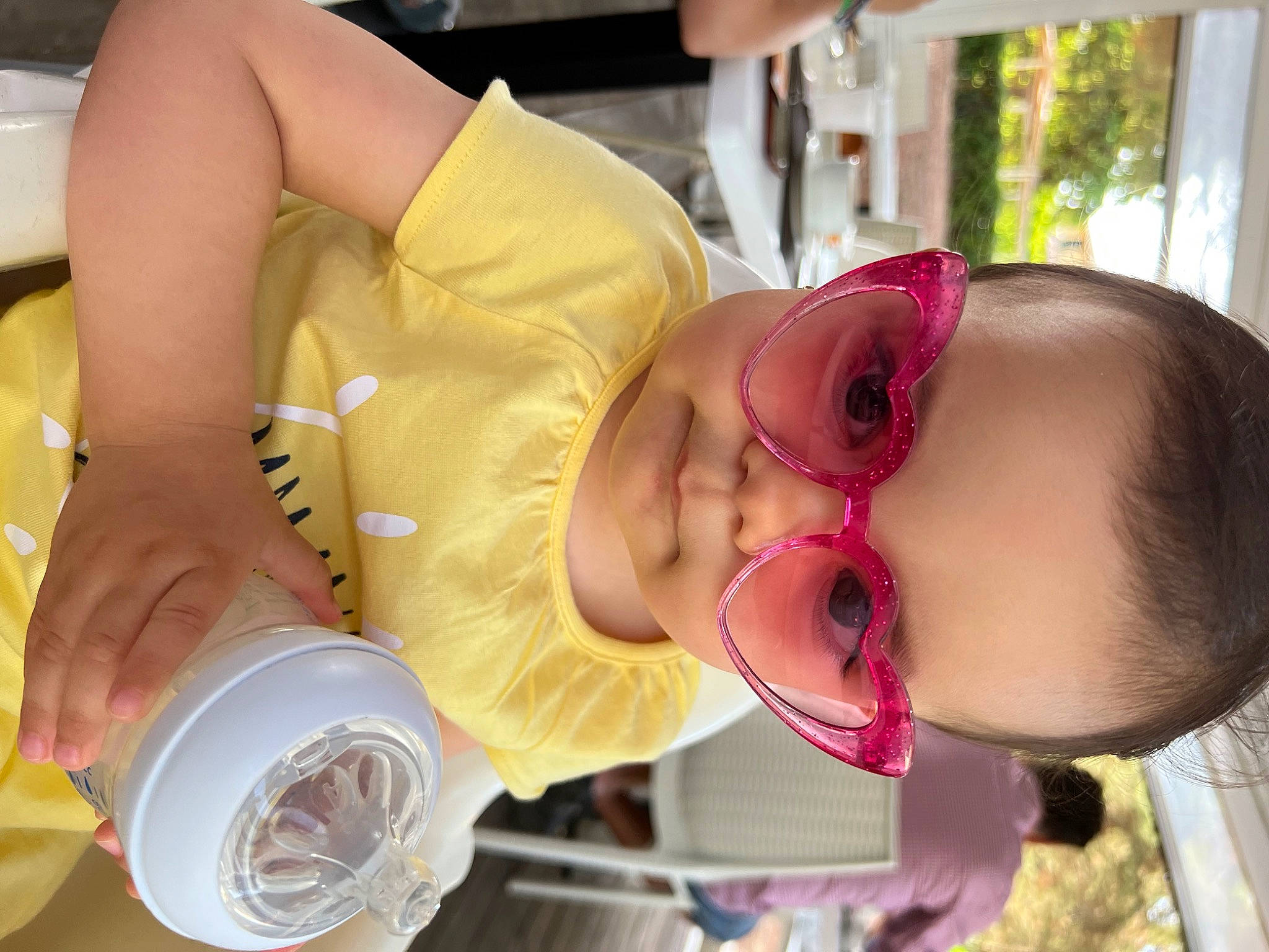 Sienna is registered to the contest to win money with this photo: arm, baby, baby_toddler_clothing, cheek, dress, eye, eyelash, eyewear, food, glasses, goggles, happy, mouth, person, pink, skin, smile, sunglasses, tableware, toddler