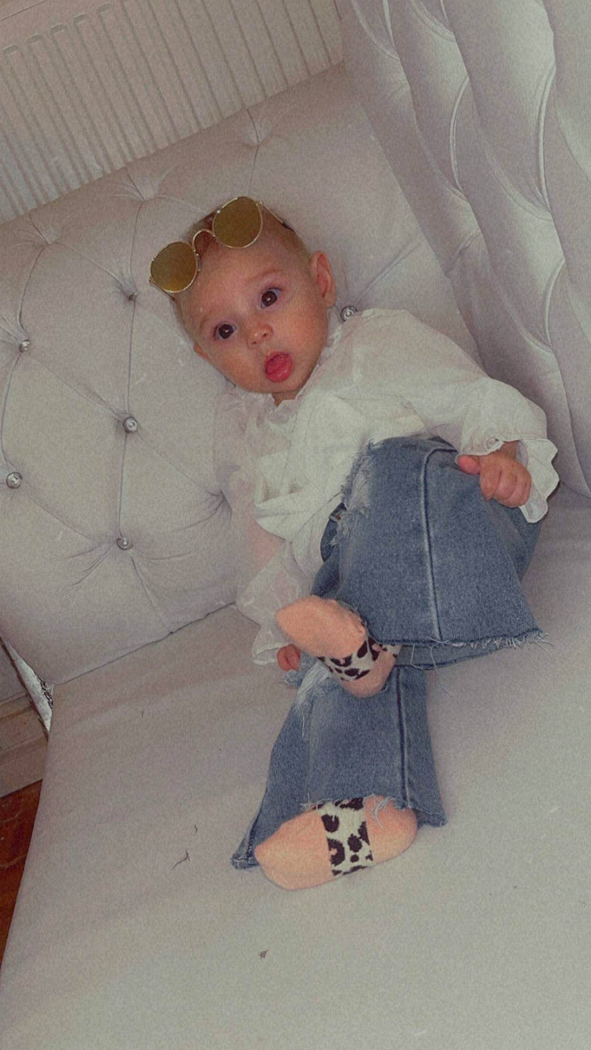 Evelyn participe au concours pour gagner de l'argent avec cette photo : baby, baby_products, baby_toddler_clothing, child, comfort, day_dress, flooring, foot, headwear, human_leg, knee, linens, pattern, person, room, sitting, sleeve, sock, surprise, textile