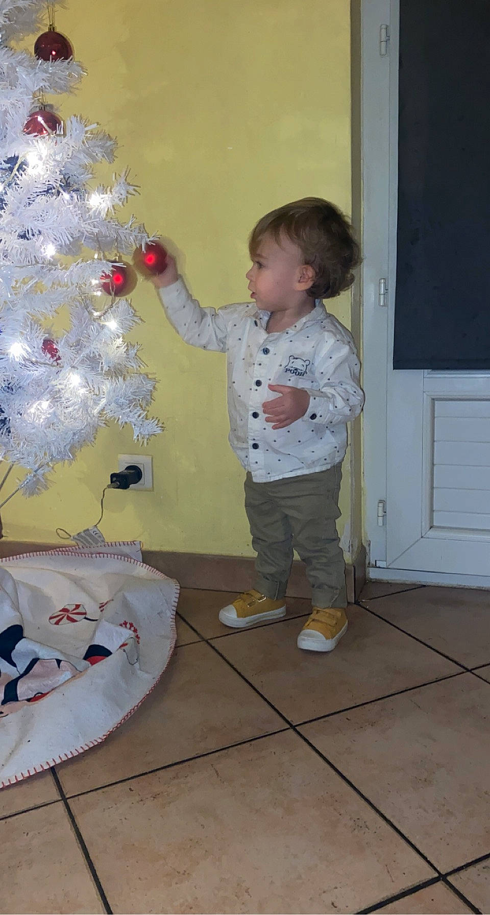 Aaron a rejoint le concours — aidez-le/la à gagner de superbes lots ! baby_toddler_clothing, child, christmas_decoration, christmas_ornament, christmas_tree, door, event, evergreen, flooring, fun, hardwood, holiday, holiday_ornament, ornament, person, play, room, standing, toddler, tree