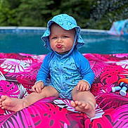 Rhett is registered to the contest to win money with this photo: baby, child, pool, inflatable, float, swimsuit, hat, blue, pink, water, outdoor, summer, pucker, funny_face, toddler, toy, greenery, nature, sitting, cute
