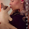 affection, animal, blond_hair, casual, cat, close_up, cute, earbuds, face, headband, holding, human, indoor, interaction, kissing, love, pet, portrait, warm_lighting, woman