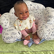 Deborah is registered to the contest to win money with this photo: baby, baby_bouncer, bib, blanket, child, cozy, cushioned_seat, dark_background, facial_expression, floral_pattern, happy, indoor, infant, photography, pink_clothing, portrait, safety_harness, seated, smiling, teddy_bear