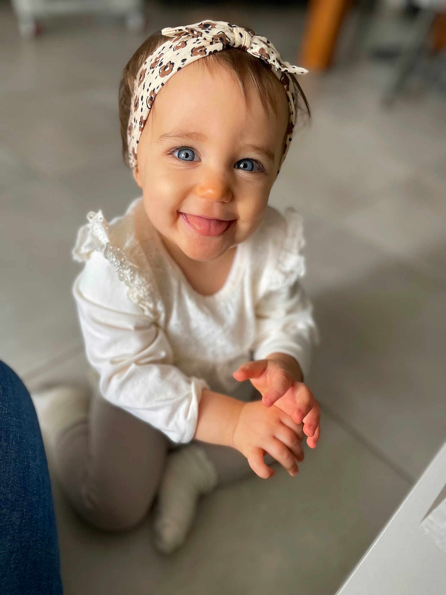 Lèsia a rejoint le concours — aidez-le/la à gagner de superbes lots ! baby, blue_eyes, candid, child, closeup, cute, floor, hands, happy, headband, indoor, infant, person, playful, portrait, sitting, smiling, tongue_out, white_clothing, young_child