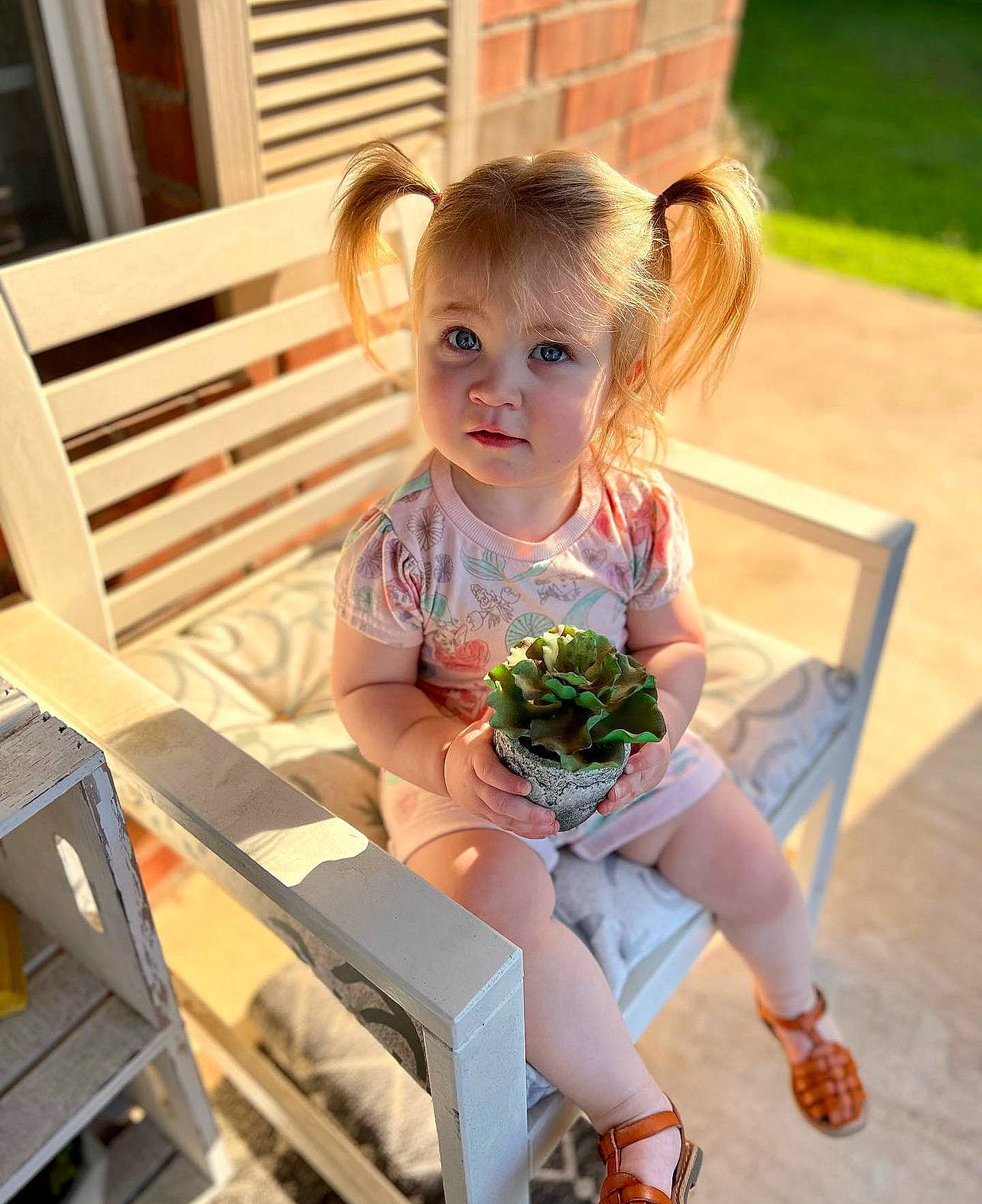 Kinsley is registered to the contest to win money with this photo: baby, baby_toddler_clothing, blond, child, flooring, fun, grass, happy, hardwood, leisure, outdoor_furniture, person, sandal, shipping_box, shoe, sitting, smile, sneakers, summer, toddler