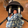 Adonis joined the competition — help win amazing prizes! baby, blanket, stroller, shopping_cart, floor, indoor, child, person, infant, black_hair, blue_blanket, checkered, seat_belt, retail, store, shopping, curious, comfort, casual, young