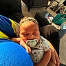 baby, pacifier, sleeping, arm, blue_shirt, gray_onesie, anchor_pattern, hand, black_chair, ottoman, water_bottle, carpet, basket, paper, living_room, sunlight, indoor, person, comfort, resting