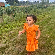 Ixchel is registered to the contest to win money with this photo: child, girl, orange_dress, boots, grass, flower_garden, sunflowers, vintage_truck, outdoor, smiling, curly_hair, nature, daylight, cloudy_sky, rural, greenery, playful, happy, portrait, casual