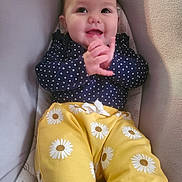 Emma joined the competition — help win amazing prizes! baby, infant, smile, clapping, polka_dot, navy_blue, yellow_pants, daisies, cute, happy, face, child, seated, cushion, indoor, portrait, clothing, hands, eyes, joyful