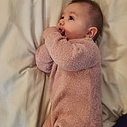 Emma is registered to the contest to win money with this photo: baby, infant, onesie, pink_clothing, blanket, lying_down, soft_texture, curious, face, hand, person, child, indoors, sleepwear, cute, newborn, skin, portrait, resting, cozy