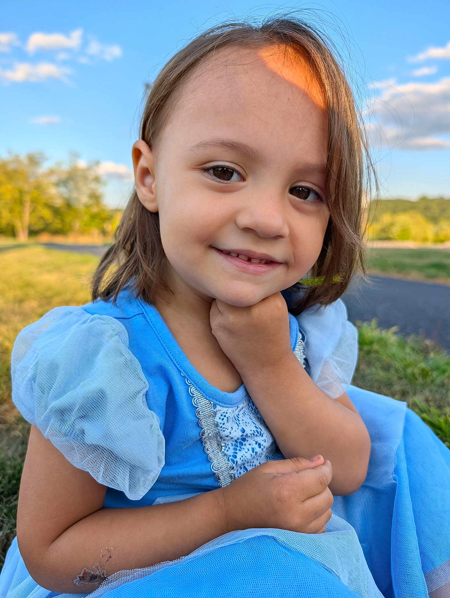 Elora joined the competition — help win amazing prizes! child, smile, blue_dress, outdoor, grass, sunlight, nature, puffy_sleeves, portrait, happy, young_girl, face, hand, daylight, person, casual, cute, scenic, closeup, innocence