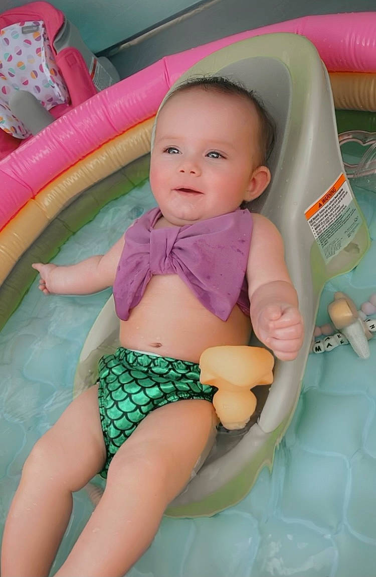 Makenzie is registered to the contest to win money with this photo: aqua, arm, baby, chest, facial_expression, finger, fun, human_body, joint, leisure, mouth, organ, person, pink, skin, smile, stomach, swimwear, thigh, toddler