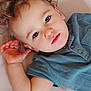 toddler, child, face, blue_eyes, curly_hair, hand, shirt, portrait, close_up, cute, baby, skin, expression, indoor, lying_down, person, young_child, casual_clothing, relaxed, looking_at_camera