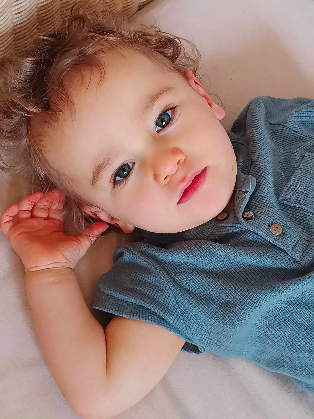 Justin participe au concours pour gagner de l'argent avec cette photo : toddler, child, face, blue_eyes, curly_hair, hand, shirt, portrait, close_up, cute, baby, skin, expression, indoor, lying_down, person, young_child, casual_clothing, relaxed, looking_at_camera