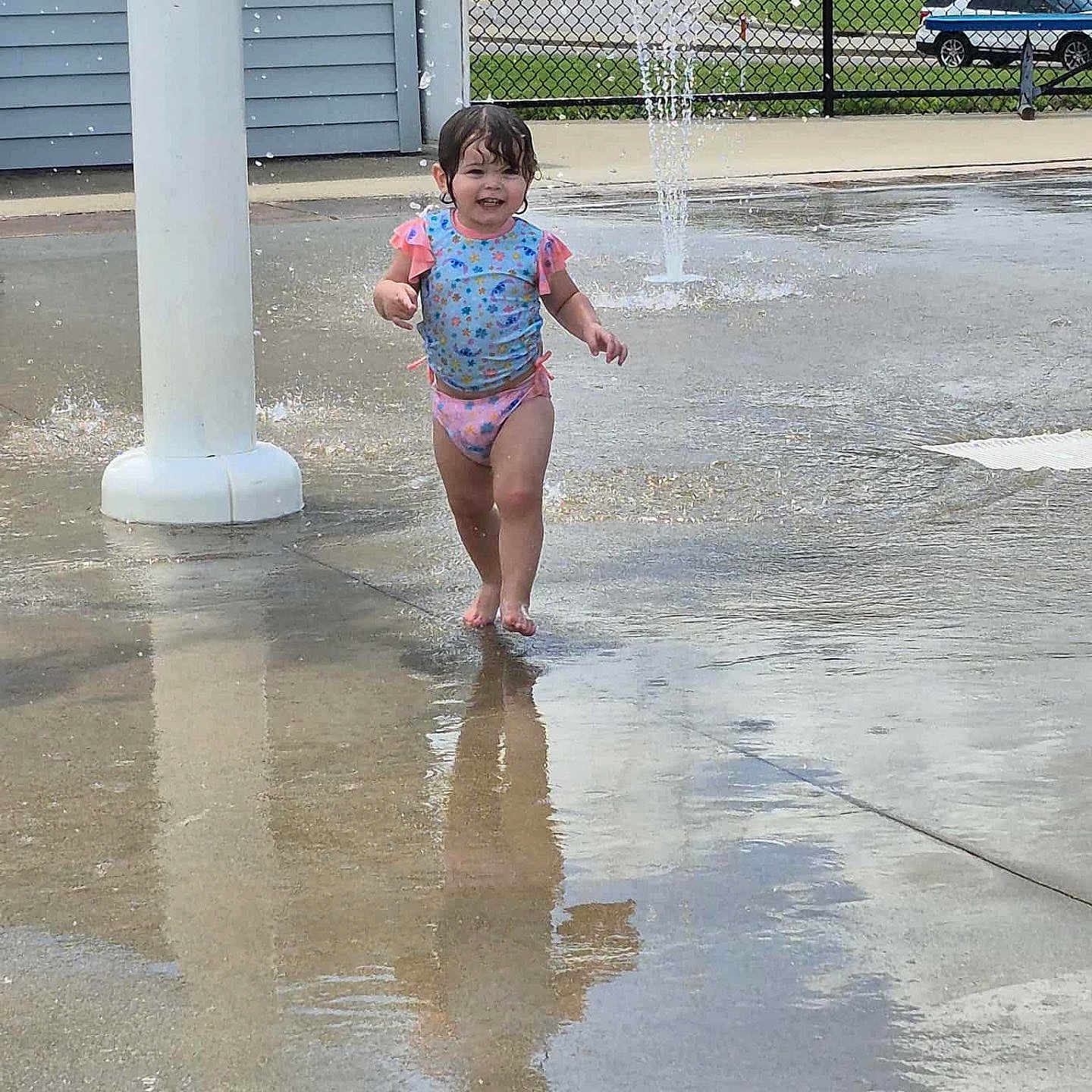 Maci is registered to the contest to win money with this photo: barefoot, casual, child, daytime, fun, happy, outdoor, play, recreation, reflection, smiling, splashing, summer, swimsuit, toddler, water, water_jet, water_play_area, wet_concrete, young_child