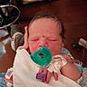 newborn, baby, pacifier, blanket, hospital, medical_tubes, infant, sleeping, hand, face, person, healthcare, indoors, bedroom, furniture, wooden_floor, tag, clothing, skin, closeup