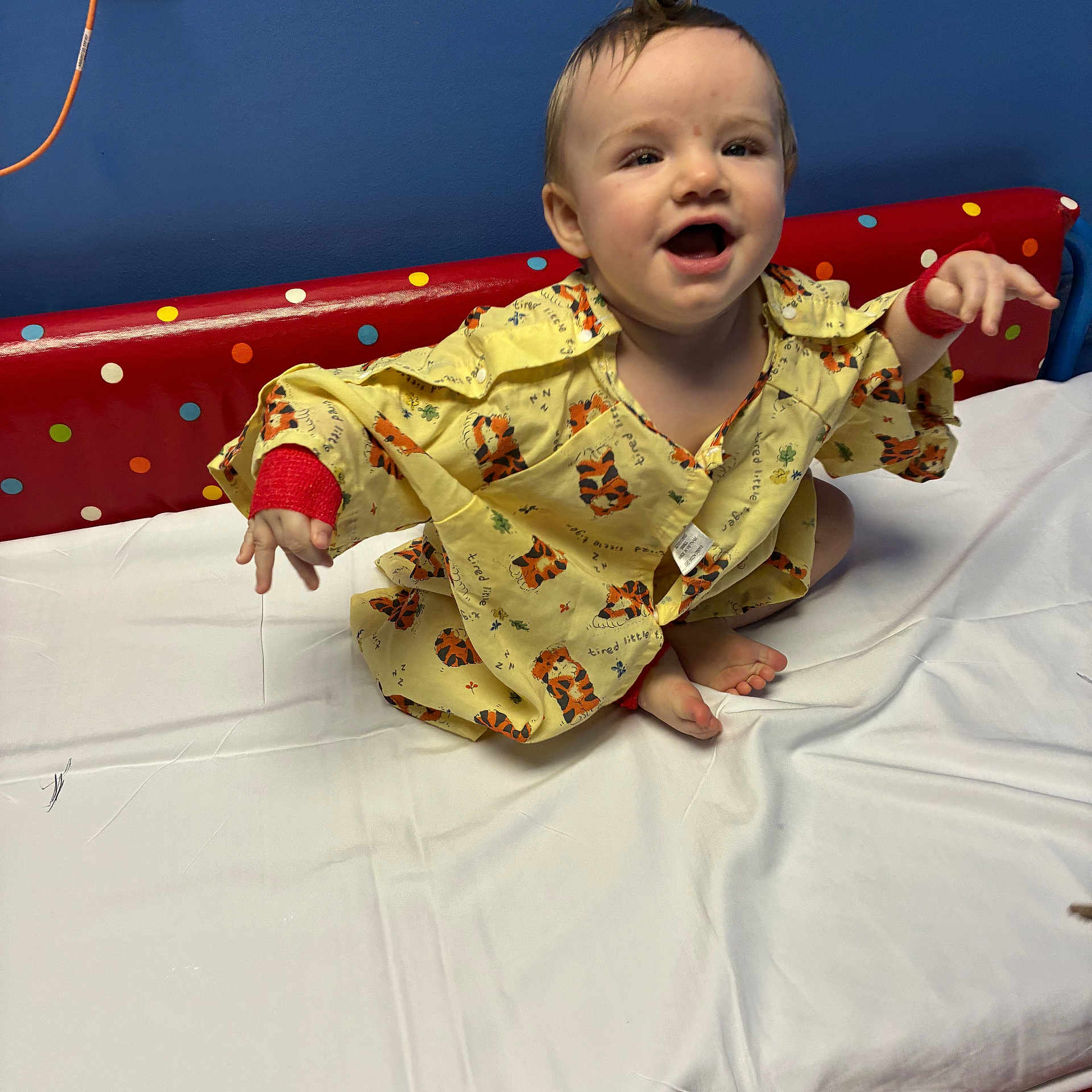 Alyocea is registered to the contest to win money with this photo: baby, bed, blanket, blue_wall, child, cute, expression, hair_style, happy, indoors, infant, person, playful, polka_dots, portrait, red_wristbands, sitting, smiling, tiger_print, yellow_gown