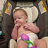 baby, infant, car_seat, toy, diaper, cute, child, face, skin, hand, legs, hair, padded_seat, warning_label, indoor, sitting, expression, colorful_toy, comfort, childcare