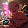 toddler, child, smiling, indoor, bedroom, curtain, window, blanket, clothing, person, furniture, messy_room, light, hair, face, happy, bed, fabric, room, casual