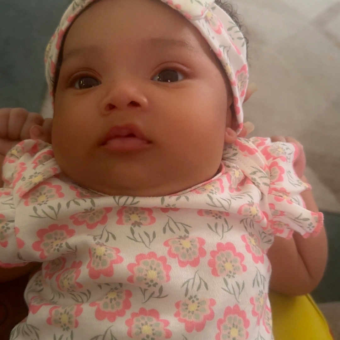 Gionna joined the competition — help win amazing prizes! baby, blurred_background, carpet, child, clothing, cute, eyes, face, floral_pattern, hand, headband, holding, indoor, infant, newborn, onesie, person, portrait, skin, soft_lighting