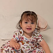 Mía joined the competition — help win amazing prizes! baby, bed, butterfly_pattern, casual, child, clothing, curly_hair, cute, dress, fun, happy, indoor, person, pillow, portrait, sitting, skin, smiling, toddler, young_child