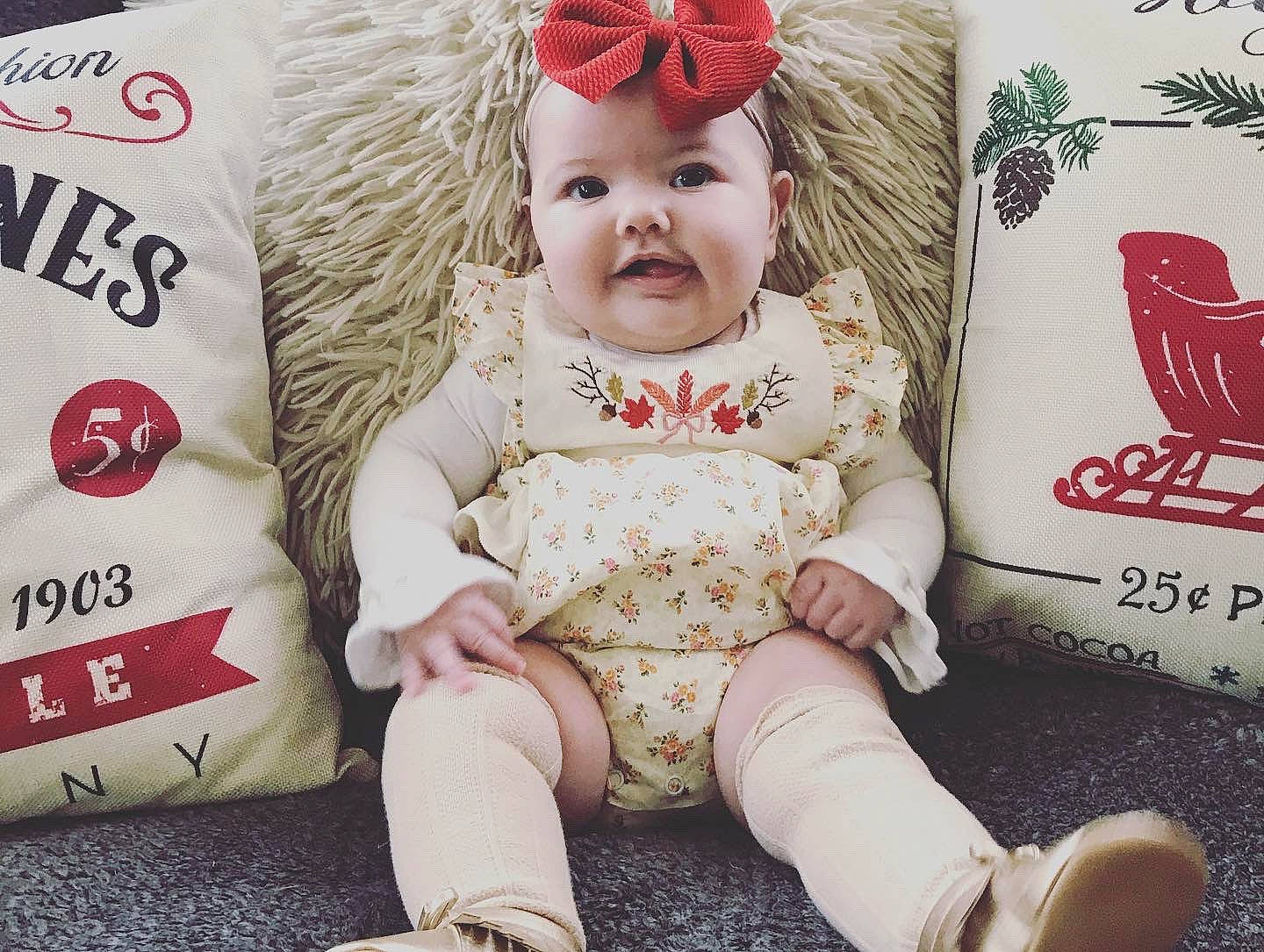 Georgia is registered to the contest to win money with this photo: baby, beige, child, christmas, design, font, head, pattern, person, product, shoe, sitting, sleeve, toddler