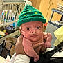 Aubree joined the competition — help win amazing prizes! baby, infant, green_hat, knitted_hat, oxygen_tube, hand, indoor, crib, person, newborn, cute, wide_eyes, portrait, child, holding, nurturing, hospital_equipment, warm_clothing, soft_lighting, close_up