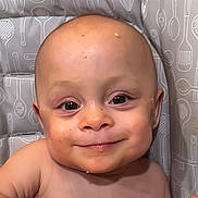 Aubree joined the competition — help win amazing prizes! baby, child, high_chair, food, crumbs, smile, face, hand, kitchen, utensil_pattern, cushion, happy, messy, cute, indoor, person, infant, young_child, cheeky, seated