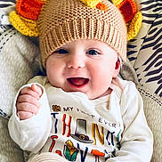 Cayson joined the competition — help win amazing prizes! baby, smiling, knitted_hat, lion_hat, thanksgiving, festive_shirt, infant, cute, happy, portrait, child, clothing, patterned_cushion, indoor, celebration, cozy, headwear, baby_gesture, joyful, closeup