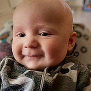 Cayson is registered to the contest to win money with this photo: baby, smiling, close_up, face, infant, cute, portrait, child, camouflage, clothing, soft_light, indoors, happy, young, skin, expression, person, head, eyes, warm