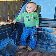 Myles is registered to the contest to win money with this photo: toddler, child, truck_bed, rust, keys, green_shirt, blue_jeans, boots, outdoor, fence, reflection, daylight, standing, person, clothing, casual, young_child, holding, vehicle, metal