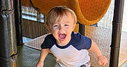 Myles is registered to the contest to win money with this photo: toddler, child, playground, indoor, slide, yellow, netting, barefoot, shorts, tshirt, happy, excited, boy, play, fun, padded_poles, smiling, active, young, casual_clothing