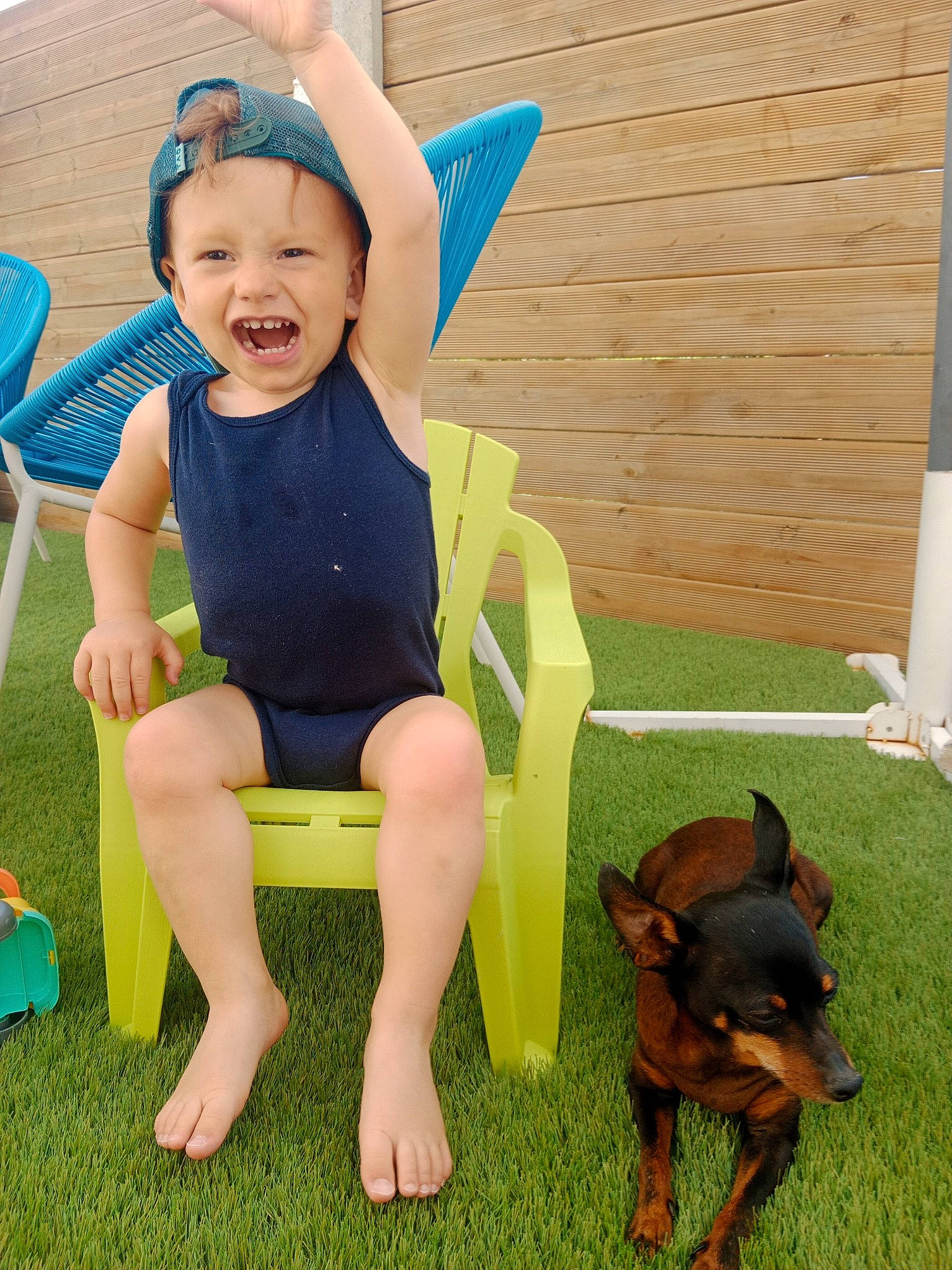 Louka participe au concours pour gagner de l'argent avec cette photo : baby_toddler_clothing, barefoot, carnivore, chair, companion_dog, dog, dog_breed, grass, happy, headwear, human_leg, joy, lap, leisure, mammal, person, sitting, smile, t_shirt, thigh