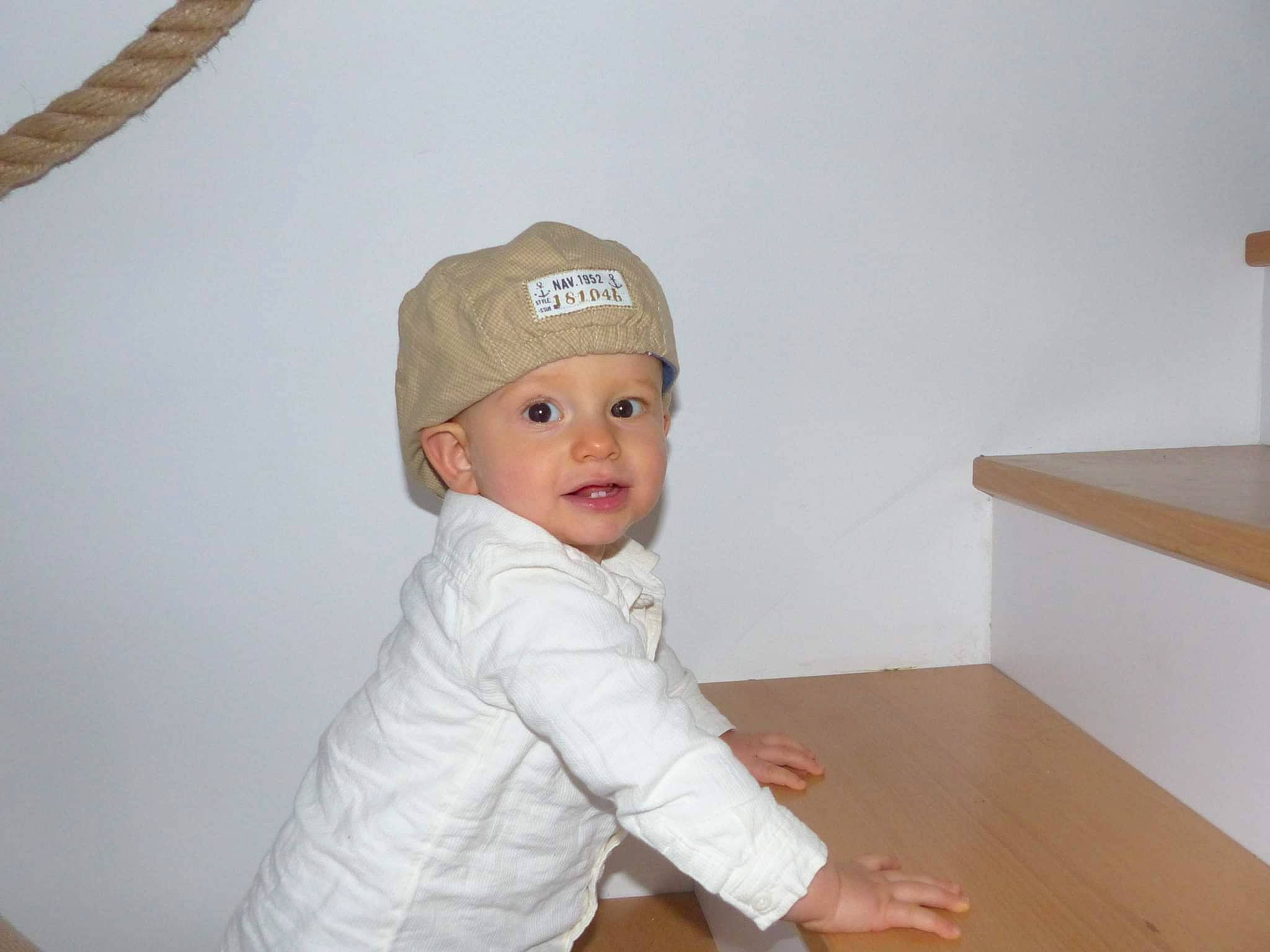 Louka participe au concours pour gagner de l'argent avec cette photo : baby, baby_toddler_clothing, baseball_cap, cap, child, comfort, fashion_accessory, flooring, fun, hardwood, headwear, person, room, sleeve, smile, toddler, varnish, wood