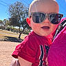baby, child, sunglasses, red_shirt, outdoor, sunny, blue_sky, tree, person, hand, smiling, happy, portrait, casual_clothing, daylight, holding, closeup, head, face, nature
