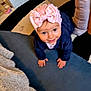 baby, child, crawling, pink_bow, hat, smiling, indoor, carpet, floor, cute, happy, person, toddler, clothing, headwear, face, young_child, playful, home, infant