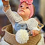 baby, child, girl, headband, pink, bow, flower, basket, woven, indoor, cute, portrait, curious, clothing, sitting, soft_focus, hand, face, expression, decor