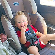 David is registered to the contest to win money with this photo: toddler, child, car_seat, smiling, red_shirt, seatbelt, interior, car, window, daylight, happy, hair, mohawk, baby, sitting, clothing, plastic_cup_holder, face, young_child, seat