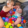 Kaleiah joined the competition — help win amazing prizes! baby, toddler, child, easter_eggs, colorful, plastic_eggs, blanket, curly_hair, headband, indoor, candid, cute, playing, interaction, sibling, smiling, soft_texture, cozy, person, family