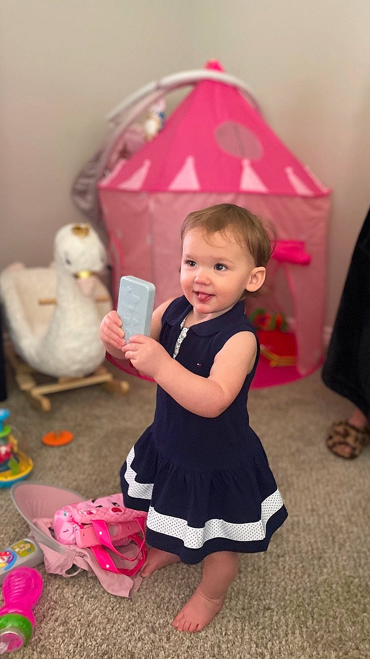 Mikayla joined the competition — help win amazing prizes! baby, baby_toddler_clothing, child, dress, event, formal_wear, fun, happy, livestock, magenta, party, person, pink, room, sandal, sitting, smile, sock, toddler, toy