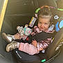 toddler, child, car_seat, car_interior, plush_toy, smiling, seatbelt, jacket, footwear, window, rainbow, unicorn, hair, person, safety, vehicle, cute, indoors, happy, playful