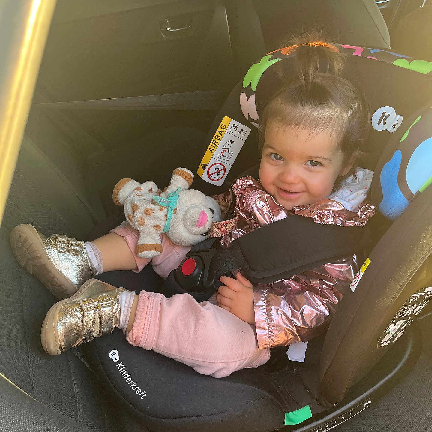 éléanore a rejoint le concours — aidez-le/la à gagner de superbes lots ! car_interior, car_seat, child, cute, footwear, hair, happy, indoors, jacket, person, playful, plush_toy, rainbow, safety, seatbelt, smiling, toddler, unicorn, vehicle, window