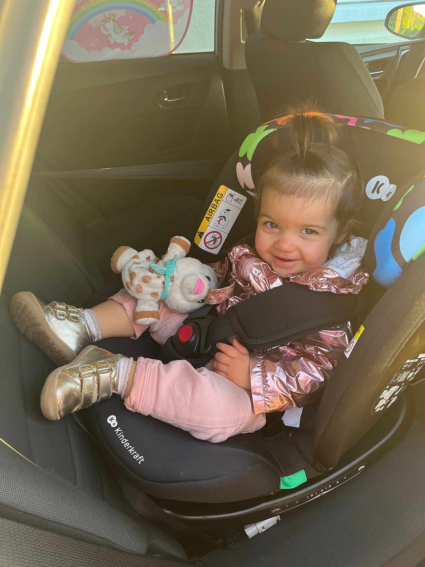 éléanore a rejoint le concours — aidez-le/la à gagner de superbes lots ! toddler, child, car_seat, car_interior, plush_toy, smiling, seatbelt, jacket, footwear, window, rainbow, unicorn, hair, person, safety, vehicle, cute, indoors, happy, playful