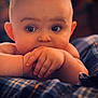 baby, infant, face, hands, eyes, skin, plaid_blanket, close_up, portrait, cute, curious, child, young, resting, soft_lighting, indoor, cozy, warm_colors, person, expression
