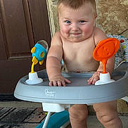 Bowen joined the competition — help win amazing prizes! baby, child, infant, smiling, portrait, activity_walker, baby_toy, orange_toy, blue_toy, indoor, door, stone_wall, seated, standing, bare_chested, happy, face, hands, legs, family_photo