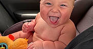 Bowen is registered to the contest to win money with this photo: baby, bare_shoulders, car_interior, car_seat, child, close_up, face, fan, happy, indoors, infant, laughing, orange_toy, plush_toy, portrait, road_trip, sitting, smiling, toy, vehicle