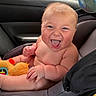 Bowen is registered to the contest to win money with this photo: baby, infant, child, smiling, laughing, face, portrait, sitting, car_seat, vehicle, car_interior, toy, plush_toy, orange_toy, fan, indoors, happy, bare_shoulders, close_up, road_trip