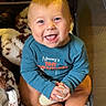 baby, infant, child, smiling, happy, portrait, sitting, bottle, blanket, plush, toy, blue_shirt, indoors, nursery, seated, bare_feet, close_up, face, cuddly, adorable