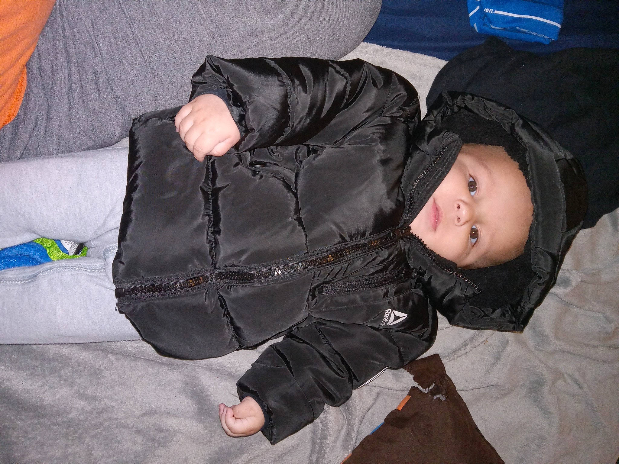 Malakai joined the competition — help win amazing prizes! cheek, child, comfort, fun, fur, headwear, human_body, jacket, person, sitting, sleeve, smile, toddler, tree, vertebrate, windbreaker, winter