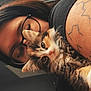 person, cat, kitten, glasses, tattoo, indoor, brick_wall, closeup, pet, furry, cute, snuggling, face, animal, warm_lighting, black_shirt, hair, whiskers, focus, portrait