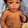 baby, bed, belly, big_eyes, blanket, bracelet, brown_skin, child, close_up, cute, dark_hair, hand, infant, jeans, month_marker, necklace, open_mouth, portrait, shirtless, wooden_sign